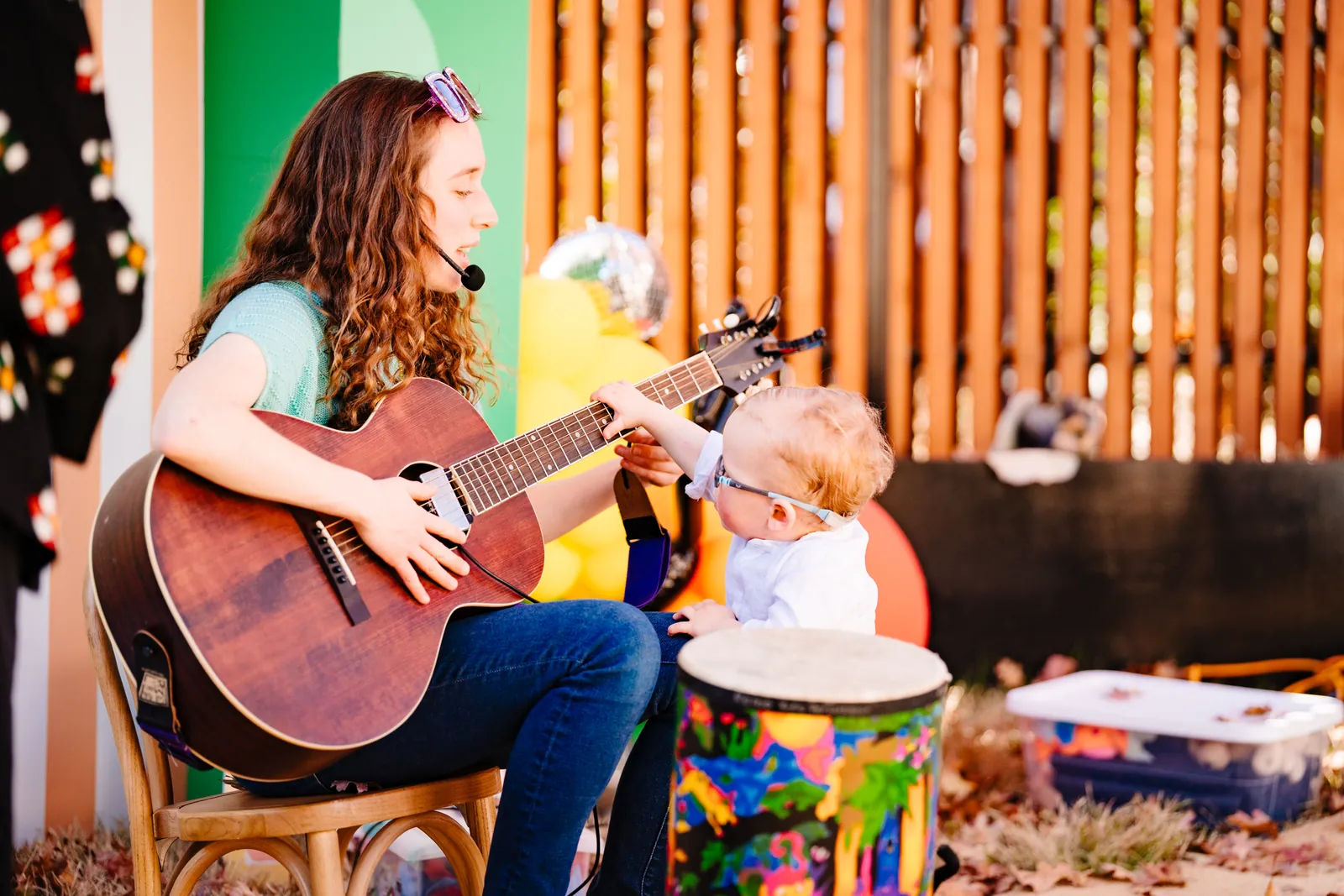 Amber playing guitar with a toddler at a disco-themed birthday party